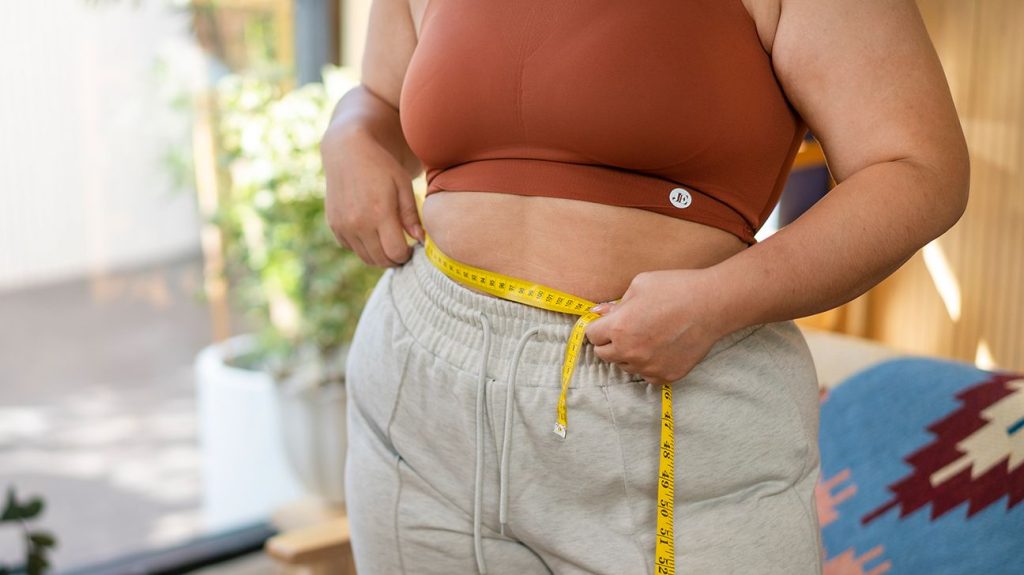 Closeup of female midsection with measuring tape