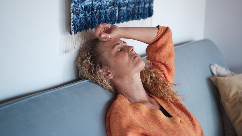 Female lying on couch with migraine