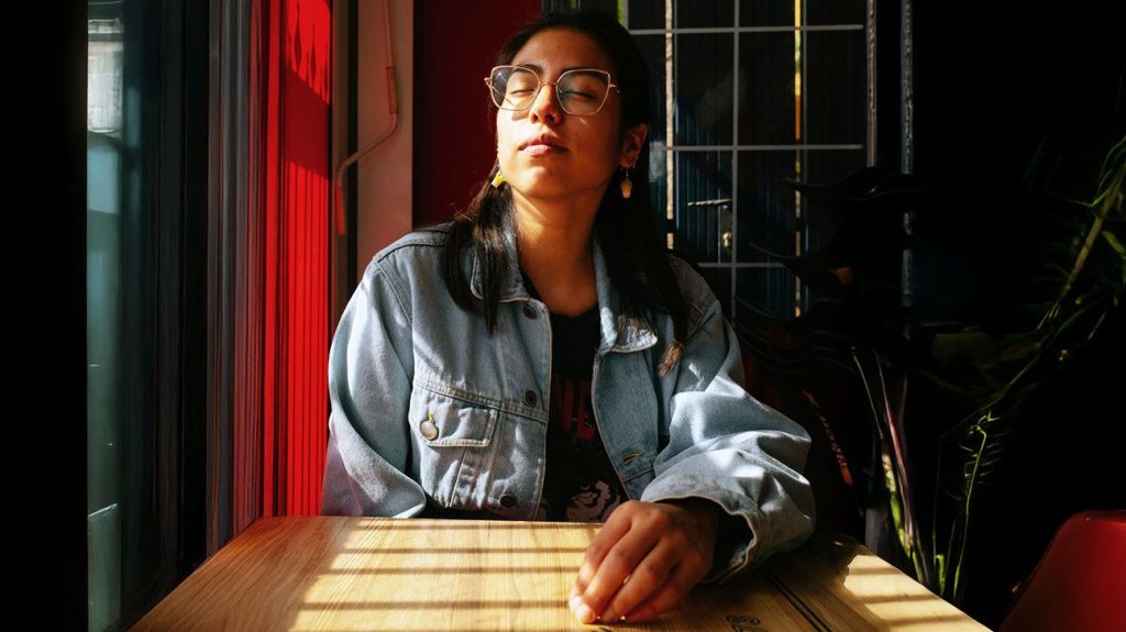 Female basking in a sunbeam by a window in a coffee shop