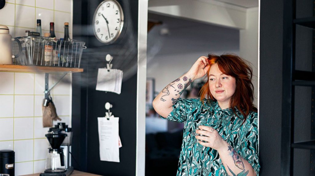 Female looks at reflection of self and clock in mirror