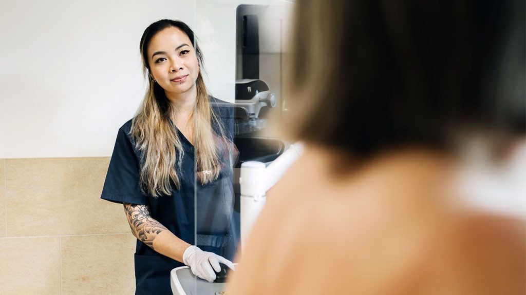Female technician performs mammogram on patient