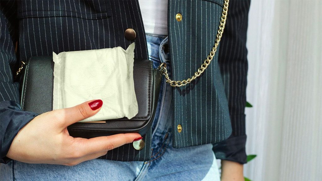 Close up of sanitary pad held outside black purse