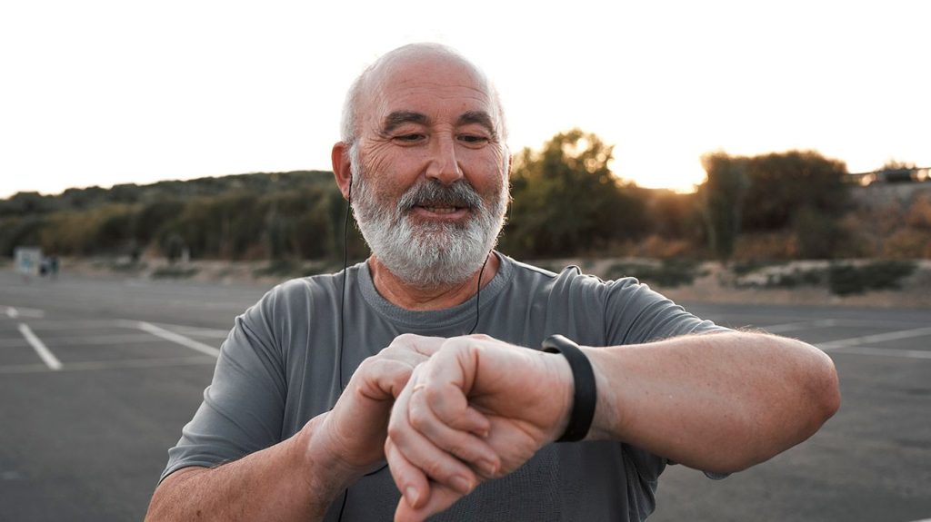 Older male checking fitness tracker outdoors