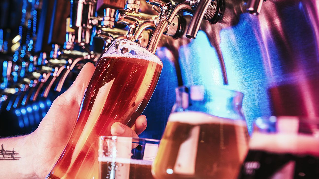 Person filling a glass of beer at a bar