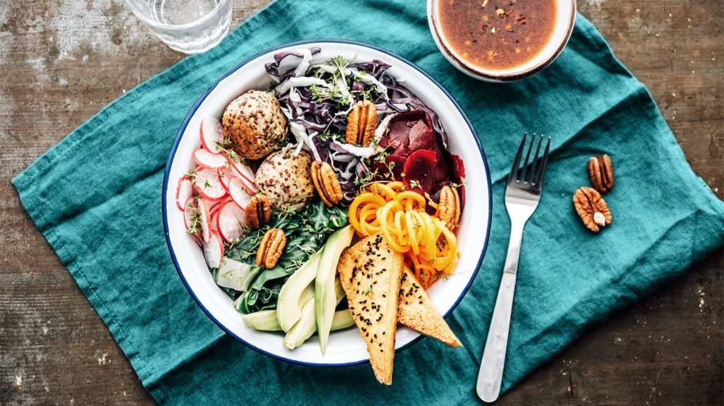 A bowl full of healthy foods on top of a teal cloth napkin