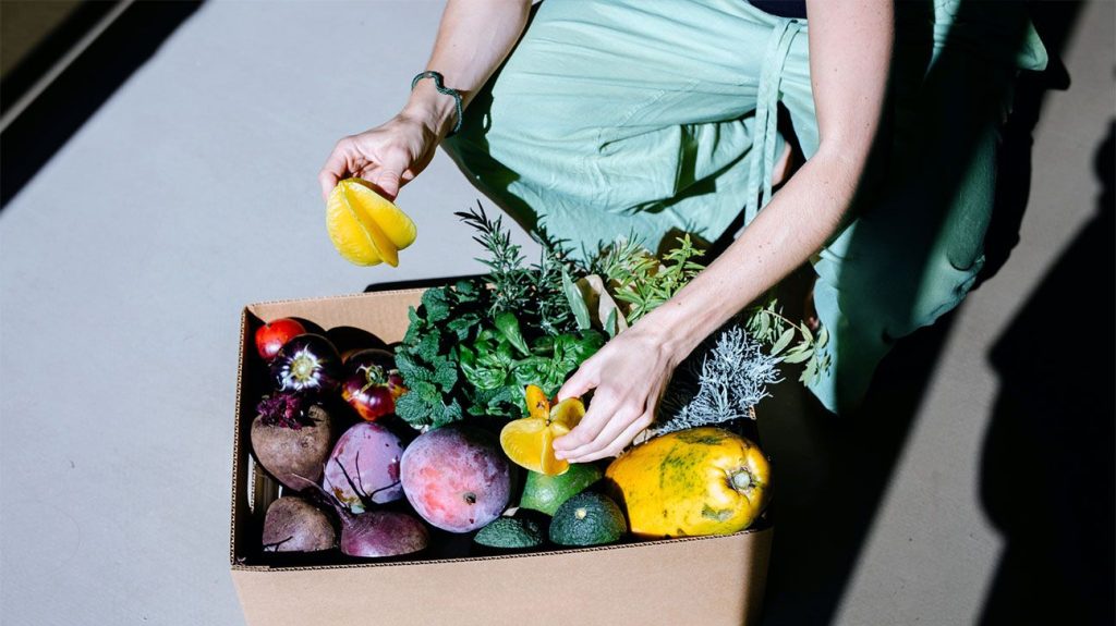 Person sorting through a box of vegetables