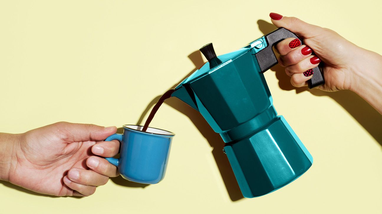 Teal coffee pot pouring coffee into a blue mug against a yellow background